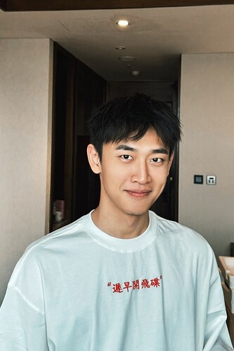 这张照片展示了一位穿着印有红色汉字的白色 t-shirt 的年轻男子，他对着镜头微微笑着。 Here are the bounding box detections:  (由 AI 生成标题)